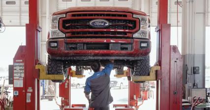 Technician working under a Ford Super Duty pickup on a lift